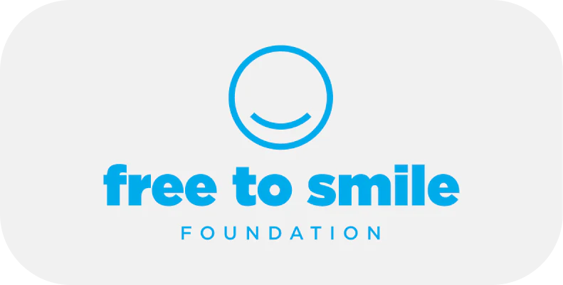 A blue logo features a smiling face above the text "free to smile FOUNDATION" on a white background with rounded corners.