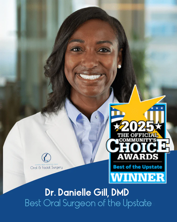 A person in a white coat smiles behind an award for "Best Oral Surgeon of the Upstate" in 2025. No landmarks visible.